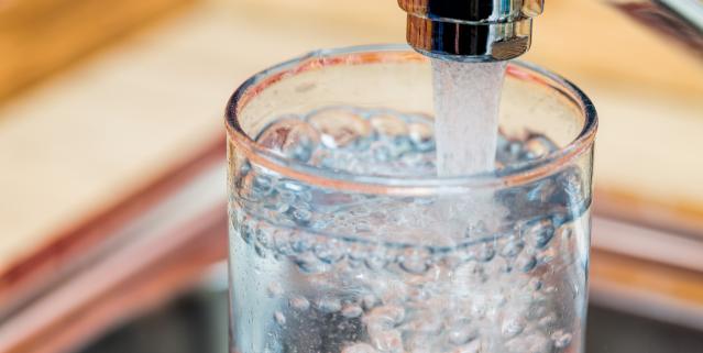 Glass under faucet filling with drinkable water